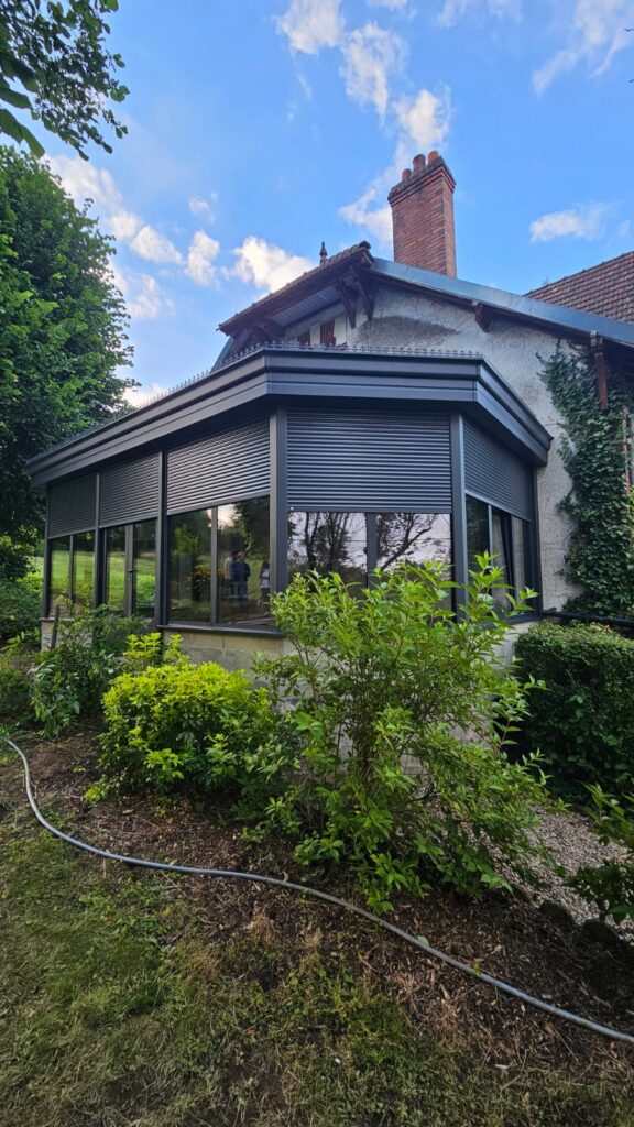 véranda aluminium noire avec volets roulants intégrés